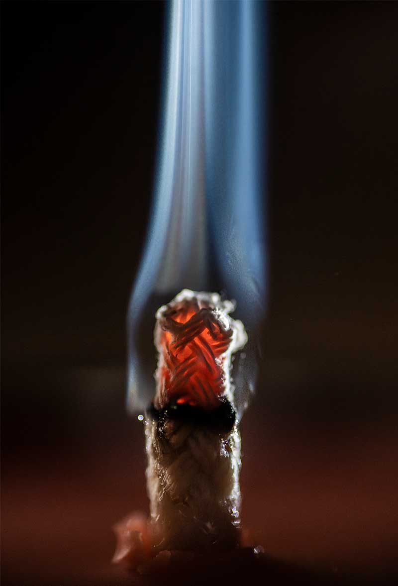 Candle wick with embers and smoke close up photography